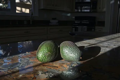 Two Fresh Avocados Resting On A Granite Kitchen Counter