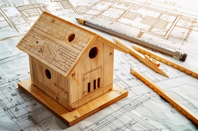 Wooden Birdhouse Model On Architectural Blueprints