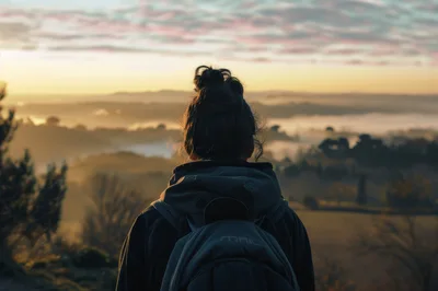 Woman With Backpack Looking At Misty Sunrise