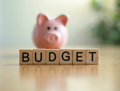 Wooden Blocks Spelling Budget With A Blurred Piggy Bank