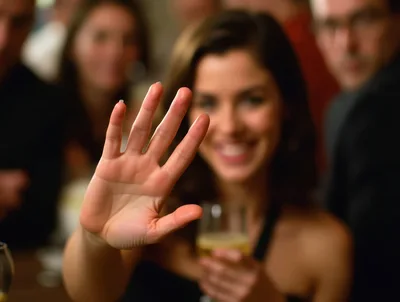 Woman Holding Up Hand In A Social Gathering