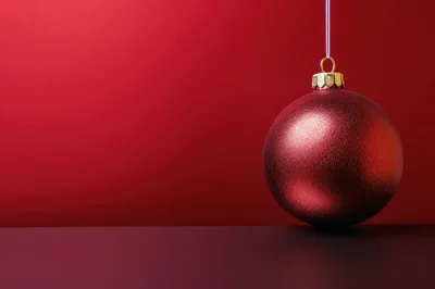Red Christmas Ornament Hanging Against Red Background