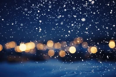 Snow Falling Over Blurred Golden City Lights