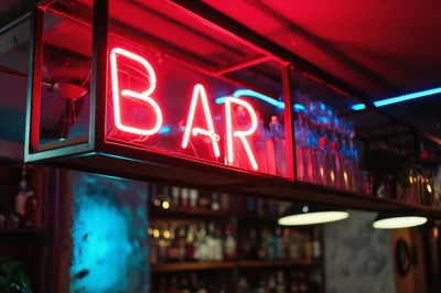 Neon Bar Sign Hanging Above A Dimly Lit Bar
