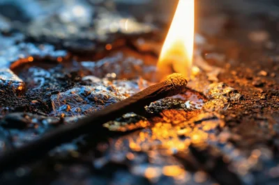 Burning Matchstick Resting On A Molten Metallic Surface