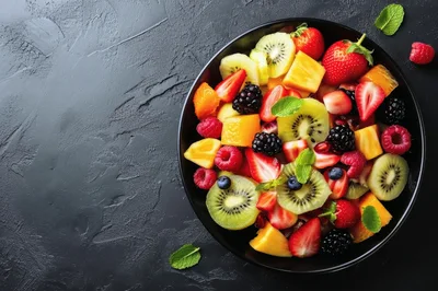 Fresh Fruit Salad in Black Bowl on Dark Surface