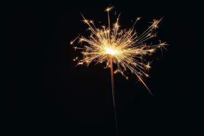 Bright Burning Sparkler Against A Dark Background