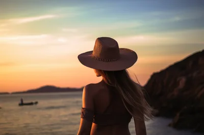 Woman Wearing Straw Hat Looking At Sunset Over Ocean