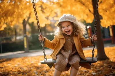 Happy Little Girl Swinging in Autumn Park