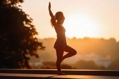 Woman Practicing Tree Pose Yoga At Sunset