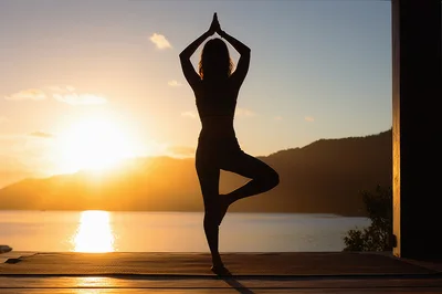 Woman Practicing Tree Pose Yoga At Sunset