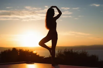 Woman Practicing Tree Pose Yoga At Sunset
