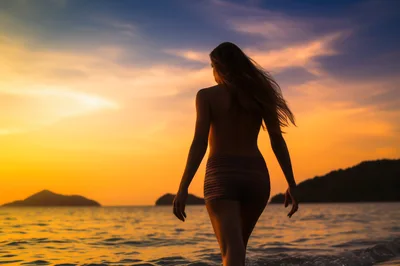 Woman Walking Into Ocean At Sunset