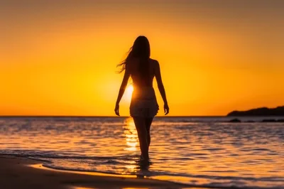 Woman Walking Into The Ocean At Sunset