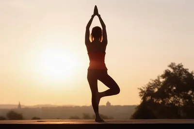 Woman Practicing Tree Pose Yoga At Sunset