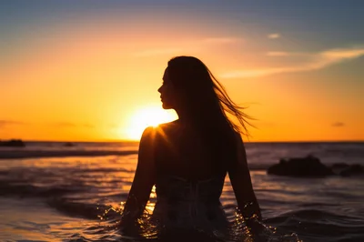 Silhouette Of A Woman Standing In The Ocean At Sunset