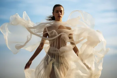 Ethereal Woman In Flowing Sheer Fabric Against Blue Sky