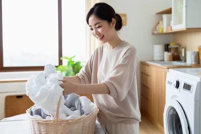 Young Asian Woman Sorting Laundry In A Bright Kitchen