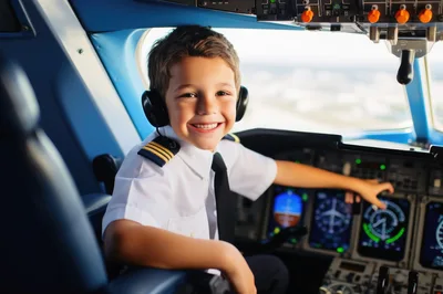 Young Boy Dressed As Pilot In Airplane Cockpit