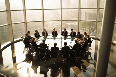 Corporate Executives Meeting Around A Large Glass Boardroom Table