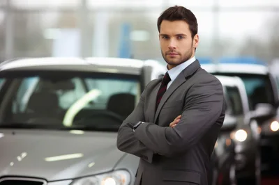 Professional Car Salesman Standing In A Dealership Showroom