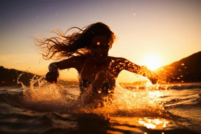 Woman Splashing Water In Ocean At Sunset