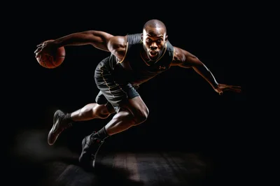 Athletic Basketball Player Dribbling Ball Against Black Background