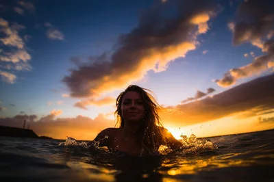 Young Woman Swimming In Ocean At Sunset