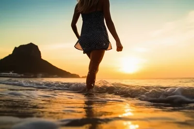 Woman Walking Through Ocean Waves At Sunset