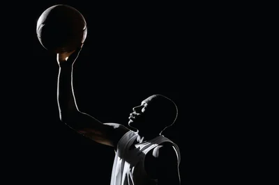 Basketball Player Reaching Up With Ball In Silhouette