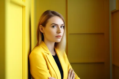 Professional Woman In Yellow Blazer Leaning Against Wall