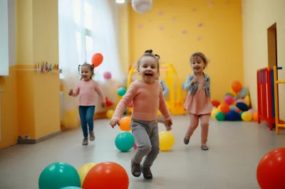 Happy Toddlers Playing With Balloons In A Preschool Classroom
