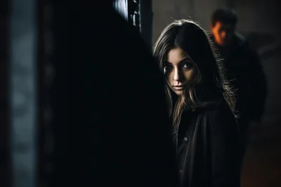 Young Woman Looking Back Over Shoulder In Dark Alley