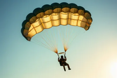 Skydiver Descending With Open Parachute Against Clear Sky