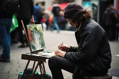 Street Artist Painting On Canvas In A Busy Plaza