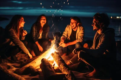 Friends Laughing Around A Beach Bonfire At Night