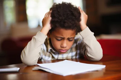 Stressed Young Boy Studying At A Wooden Table