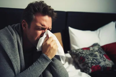 Sick Man Blowing Nose With Tissue In Bed