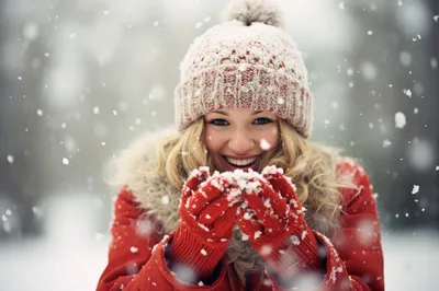 Happy Young Woman Blowing Snow From Her Hands