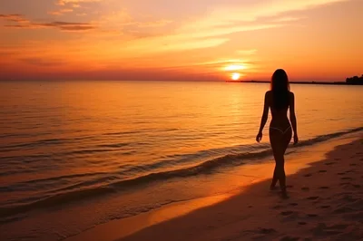 Silhouette Of A Woman Walking On The Beach At Sunset