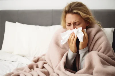 Sick Woman Blowing Nose In Bed