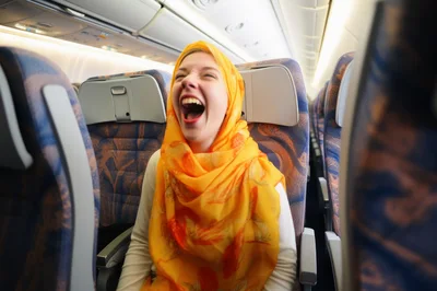 Young Woman Laughing Loudly In Airplane Seat