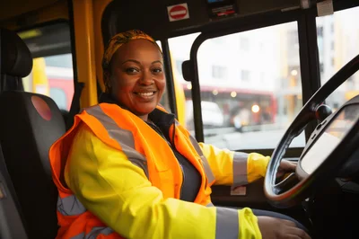 Female Bus Driver Smiling In Driver Seat