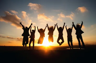 Group Of Friends Jumping In Silhouette At Sunset