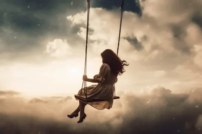 Woman Sitting On A Swing Above The Clouds