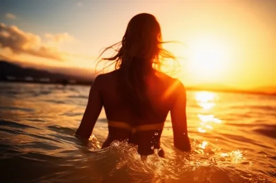 Woman Standing In Ocean At Sunset