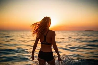 Woman Standing In Ocean At Sunset