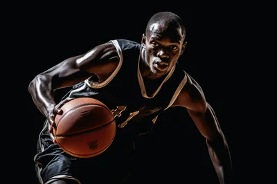 Athletic Basketball Player Dribbling Ball Against Black Background