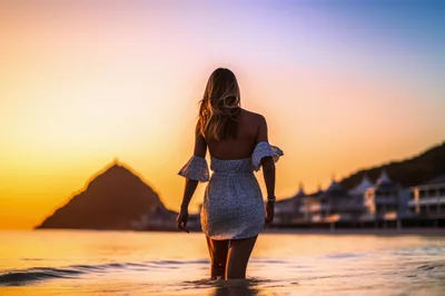 Woman Walking Into Ocean At Sunset