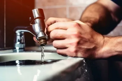 Man Repairing A Leaking Bathroom Faucet